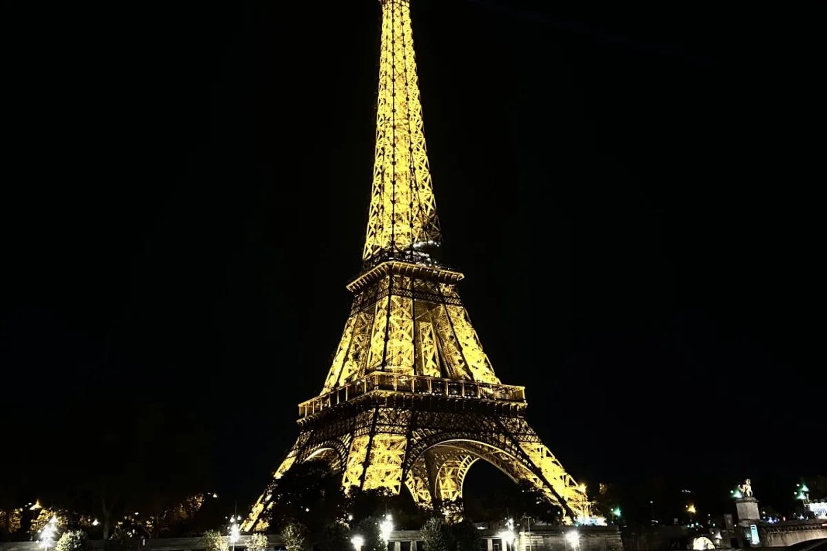 A picture of Eiffel tower from low angle, lit up at night