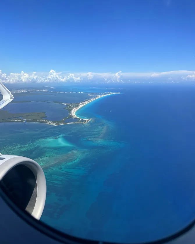 View from an aircraft of clouds and crystal clear waters below on a sunny day. 