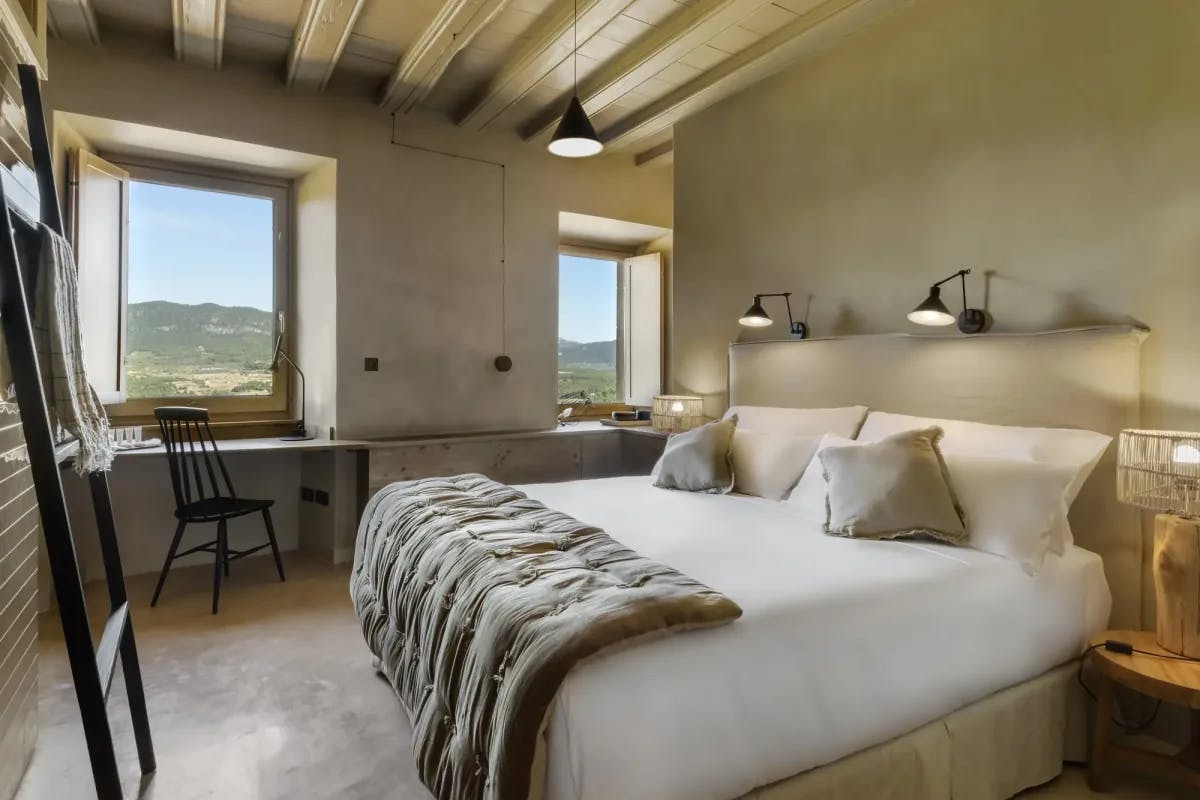 a hotel bedroom with wooden ceiling beams and a black decorative ladder