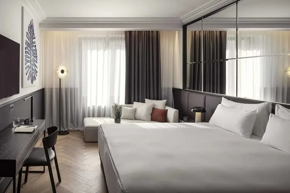 hotel room with a white bed and gray furniture and curtains