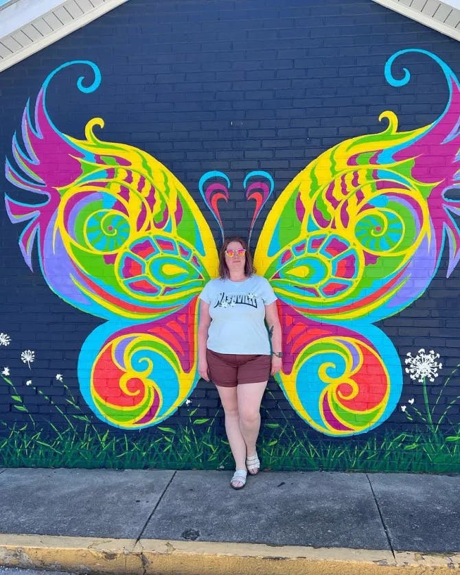 A woman posing in front of butterfly wall art.