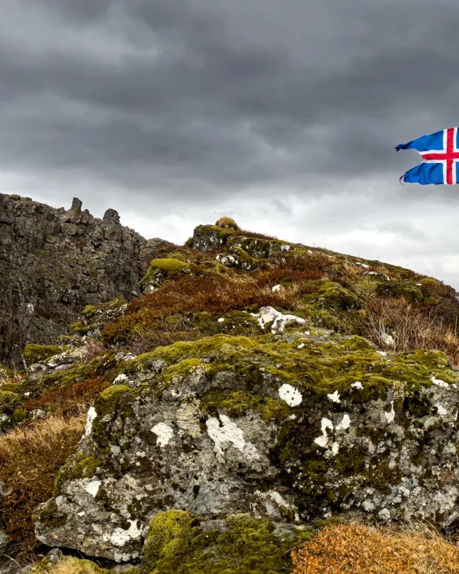A image of the top of a mountain with a UK flag on a cloudy day.