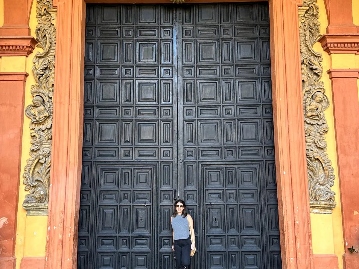 A woman standing in front of a big black door.