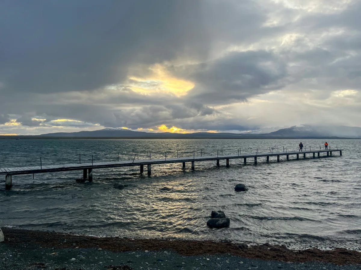 A long pier stretching into the ocean during a cloudy evening