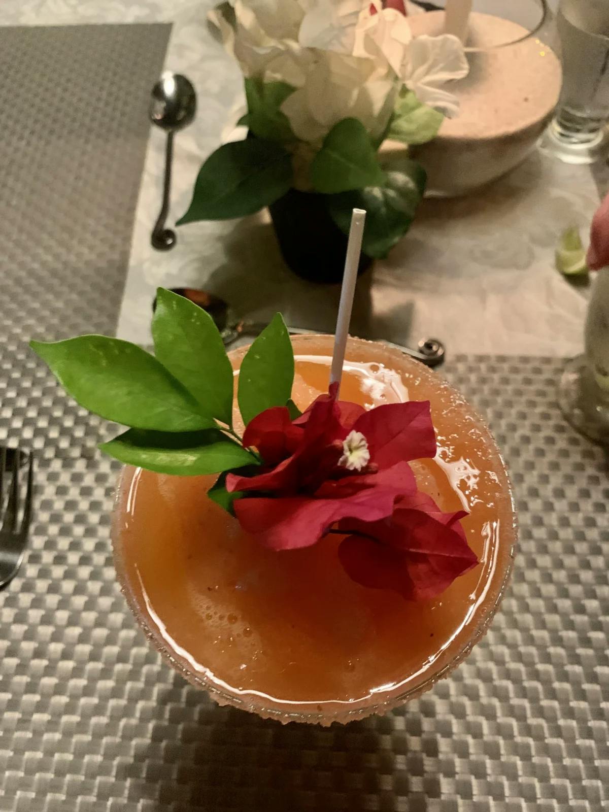 A tropical and colorful drink, topped with a floral garnish.