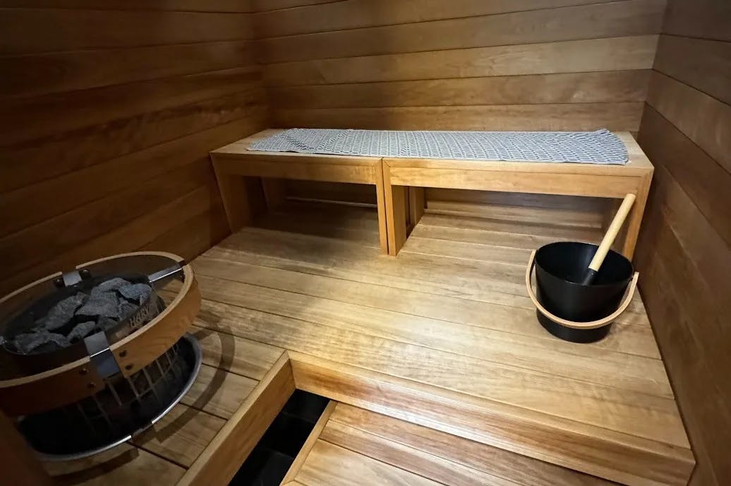 A ladle about to pour water over hot stones of a sauna.