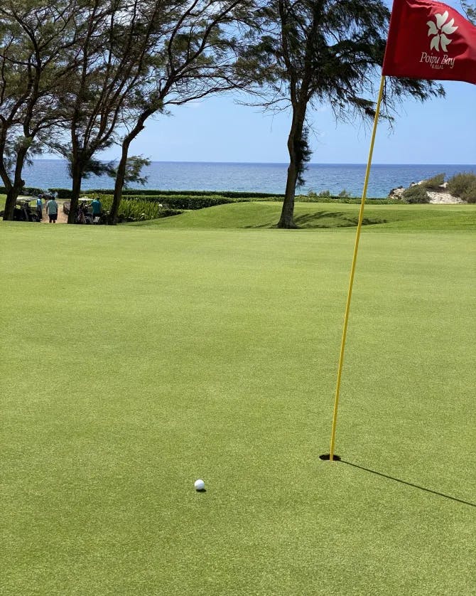 A golf course with water body at the back. 