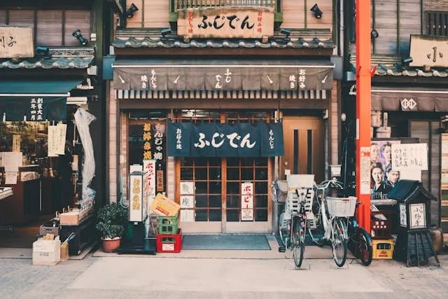 A photo of a traditional Japanese building with bicycles and crates sitting in front of it. 