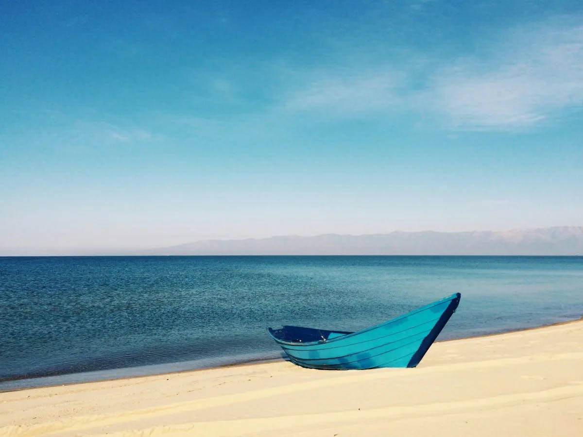 A bright blue small boat on a beautiful beach