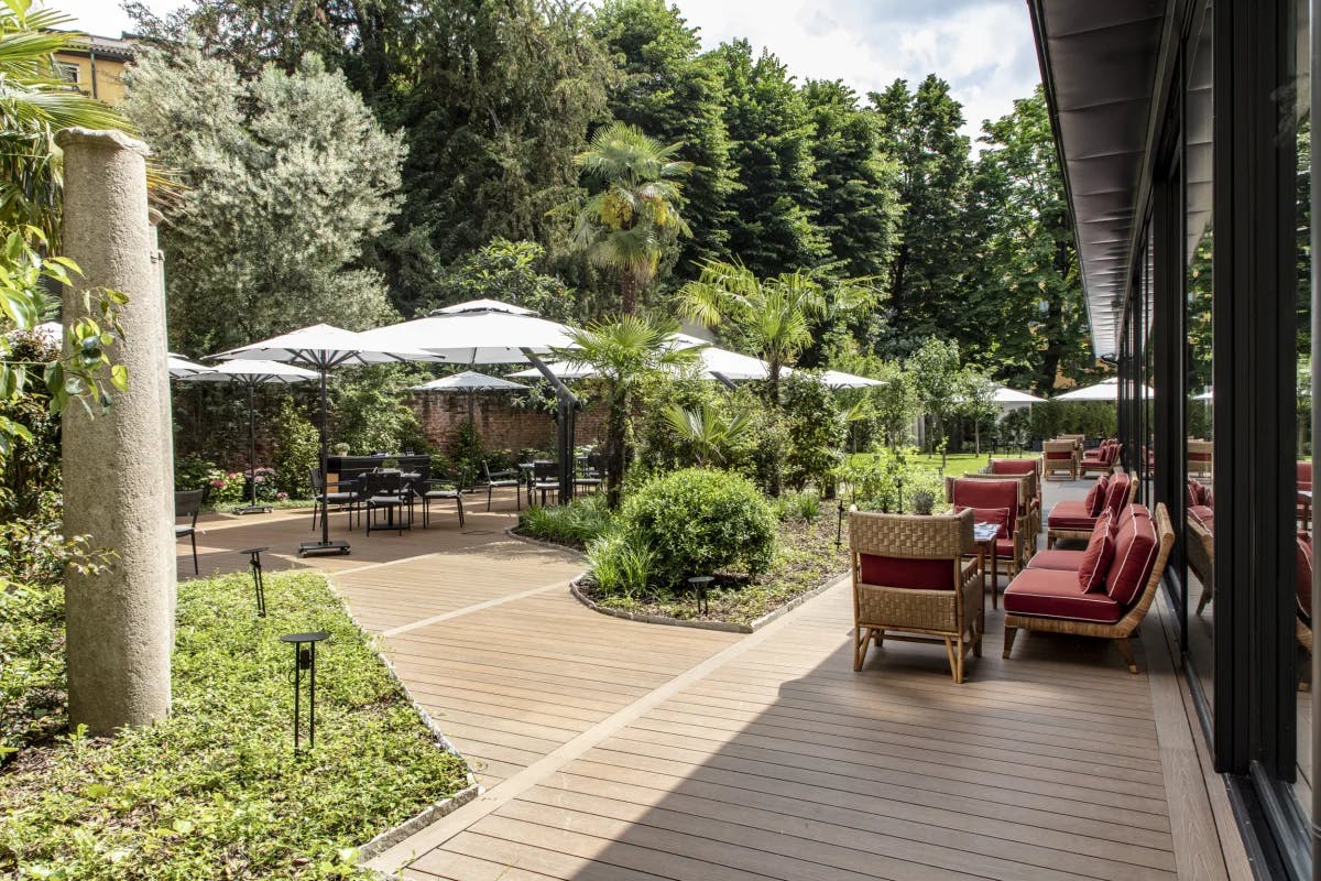 The patio at the Portrait Hotel with tables set up next to green trees