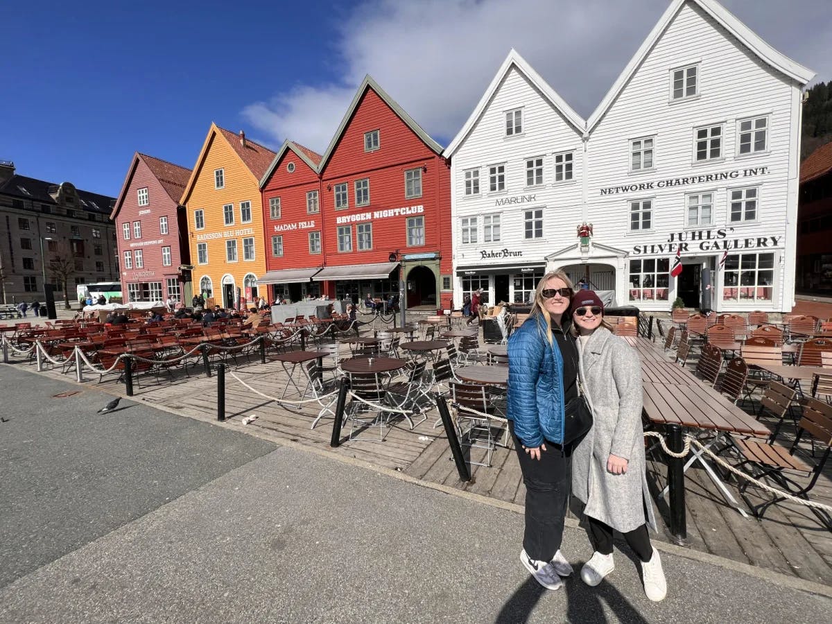 Two women standing in front of colorful buildings.