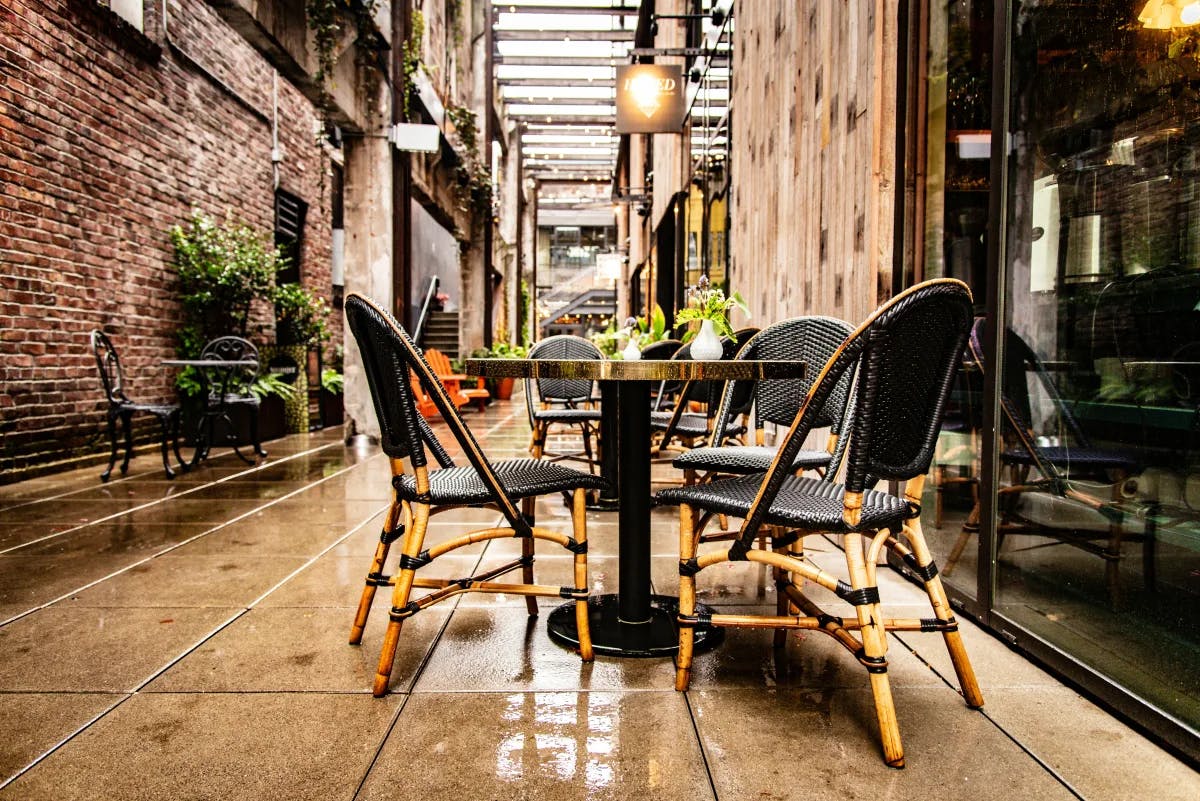 A picture of an outdoor restaurant with black metal tables and chairs during daytime.