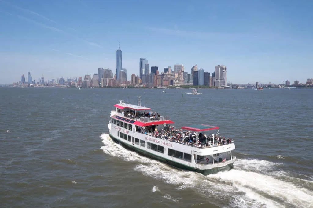 A ferry boat on the water with a city skyline in the distance