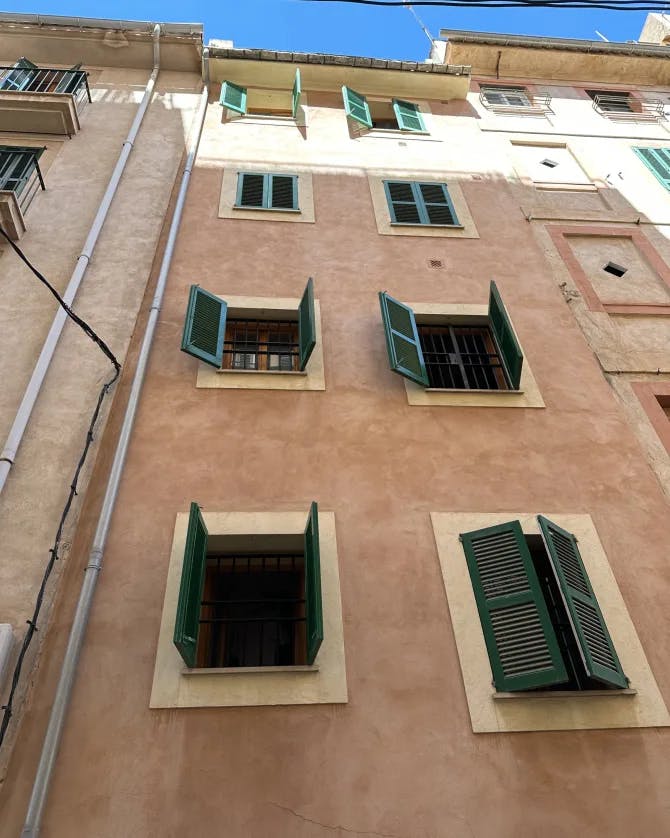 A light brown building with green windows.