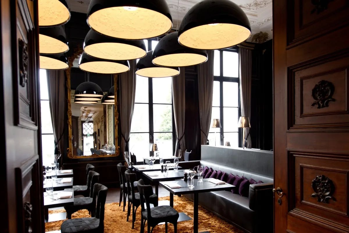 hotel dining room with dark wood doors, large round lighting and tall windows