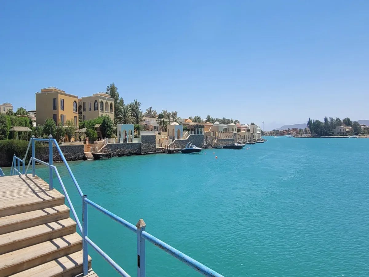 Steps against a blue railing overlooking the turquoise blue water and buildings in the distance.