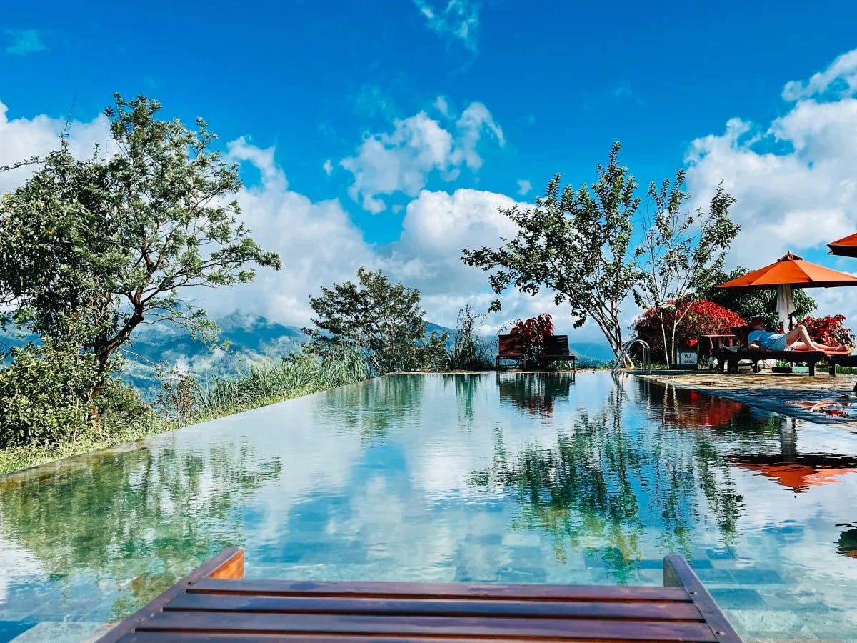 An infinity pool overlooks a mountainous landscape under a clear blue sky.