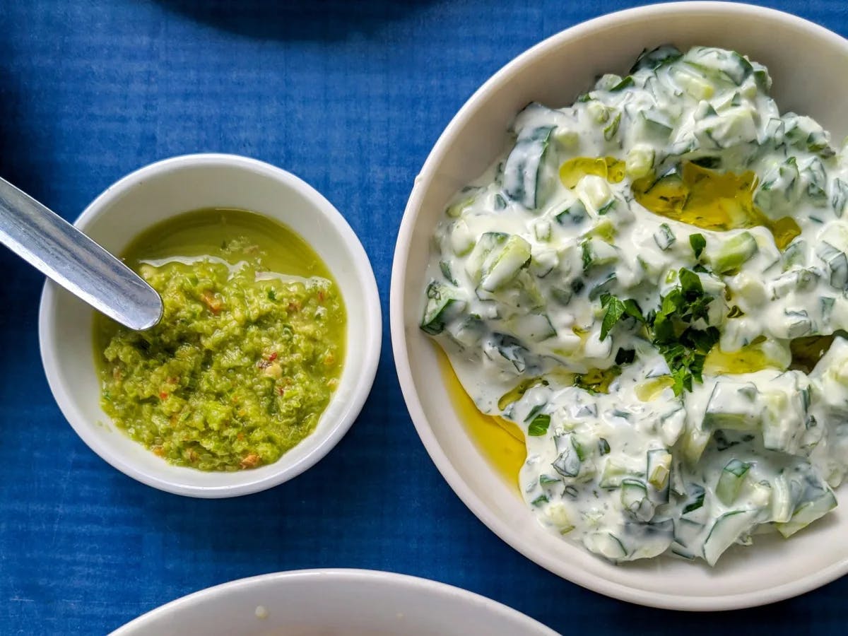 Aerial view of white bowls of Greek food on a blue table