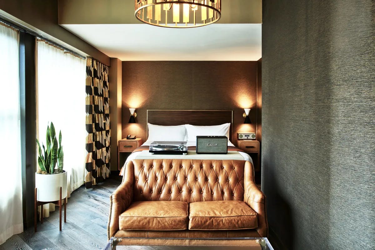 A view of the Loft Suite at the Roxy Hotel New York with brown leather sofa and dark furnishings witha vintage style