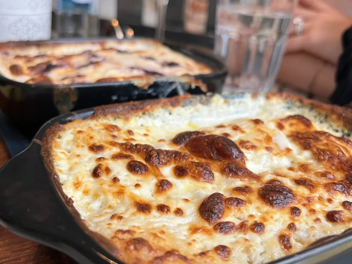 A picture of cheesy and toasted Strukli on top of a table. 