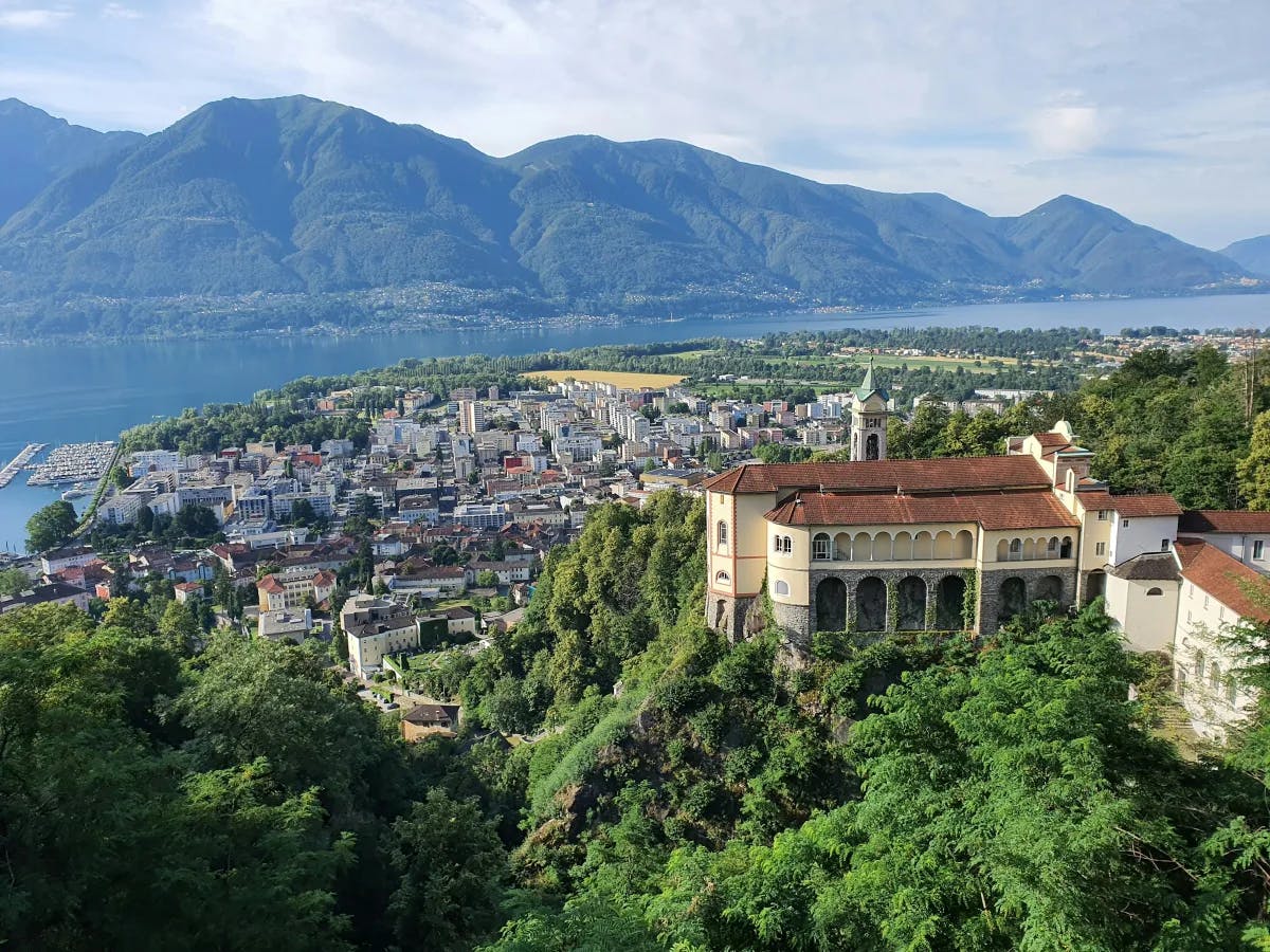 An aerial view of Locarno surrounded by trees and mountains.