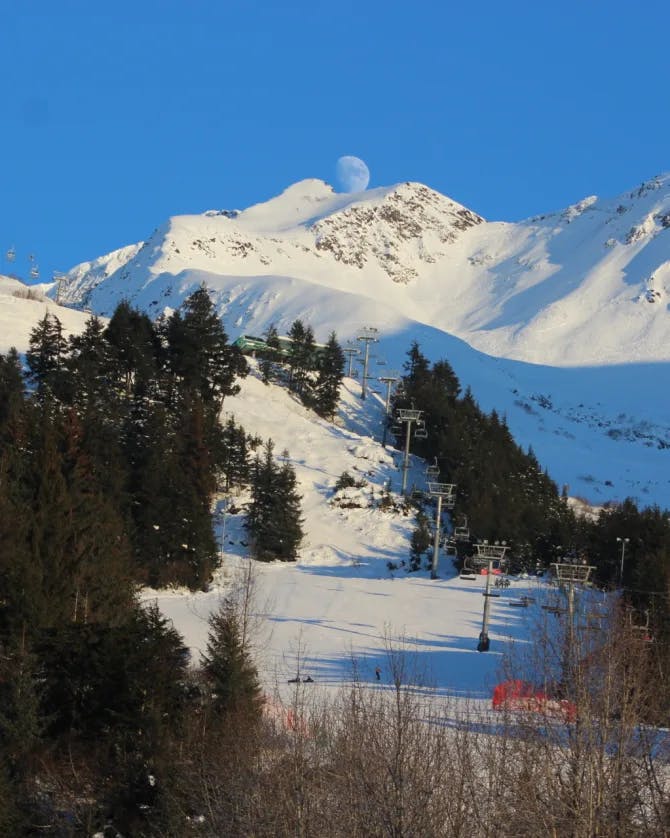 Beautiful view of snow covered mountains behind a sun-lit ski trail