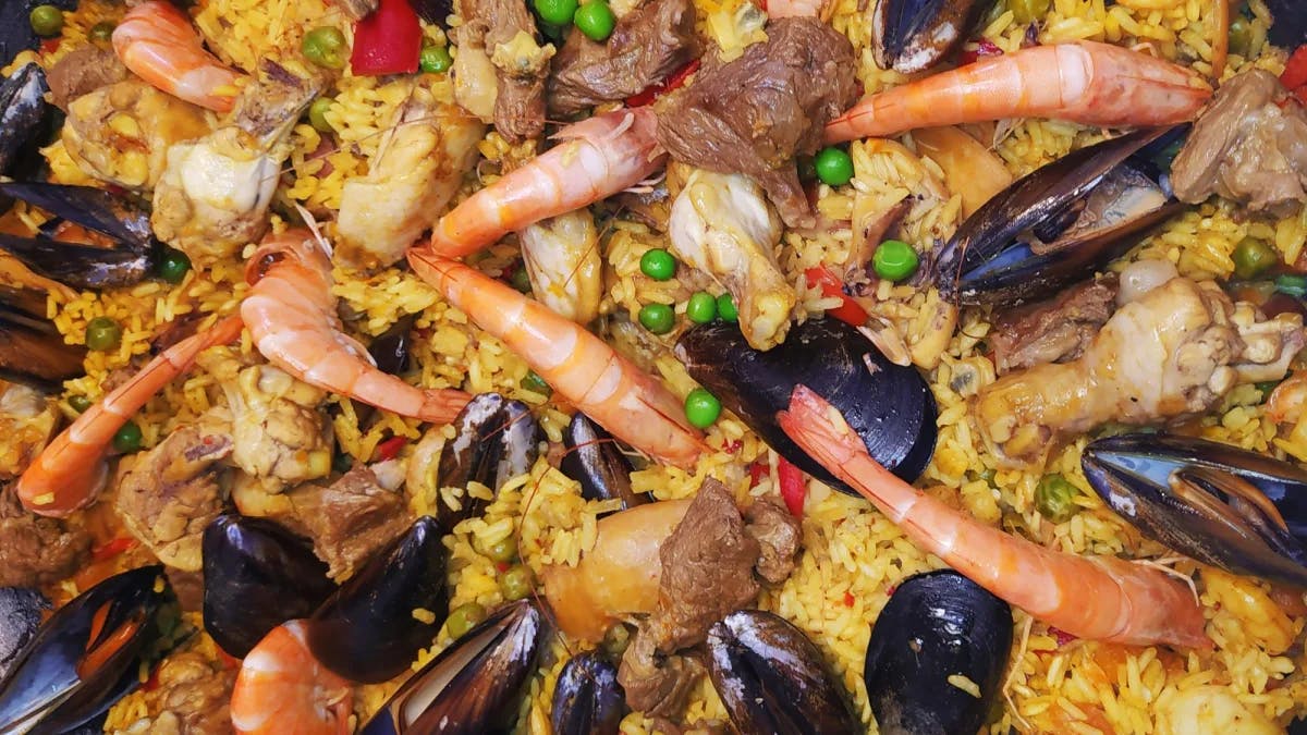 Traditional Spanish Paella with yellow rice, vegetables, mussels, shrimp and other proteins.