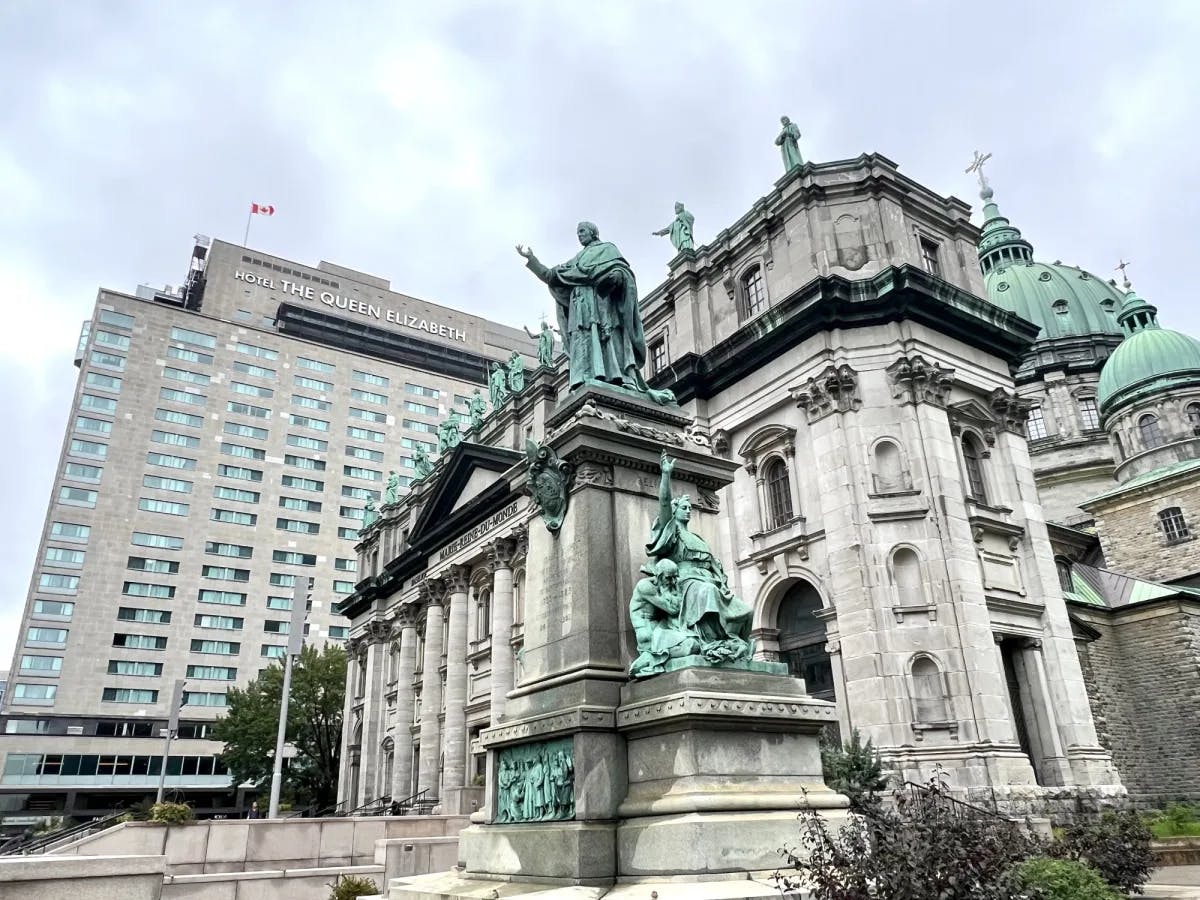 View of a city building with statues lining its walls under an overcast sky.