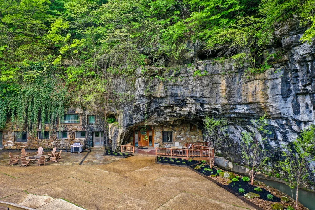 A cave resort with outdoor sitting and green trees. 