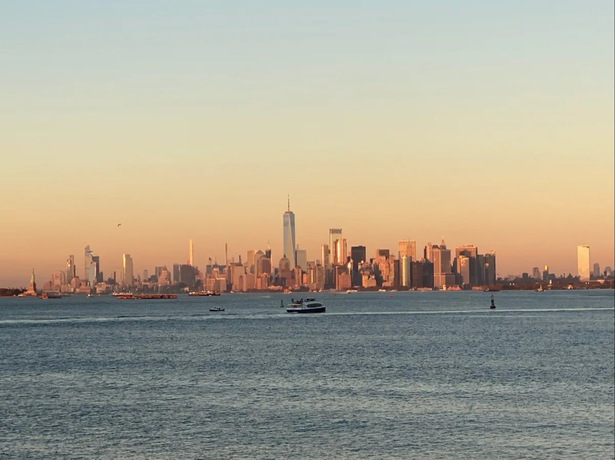 The city skyline bathed in sunset’s glow, mirrored by the tranquil waters below.