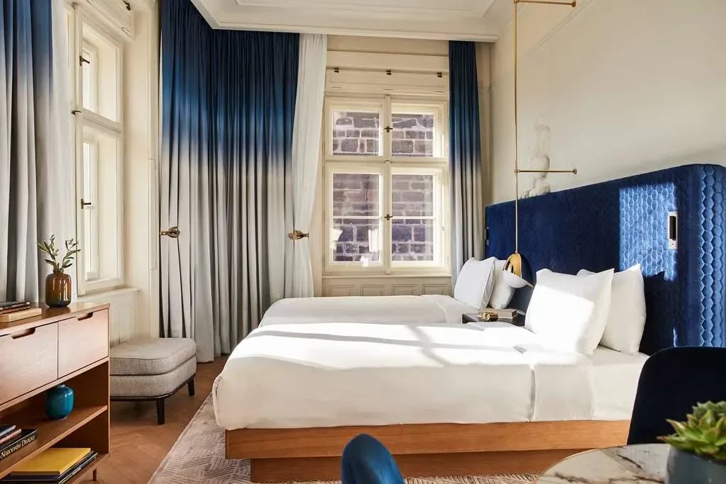 Contemporary decor with a deep-blue and pristine-white color palette denote a room with twin beds at Andaz Prague