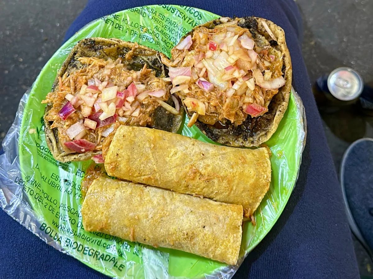 A plate of tacos on a green plate, freshly served by a street vendor.