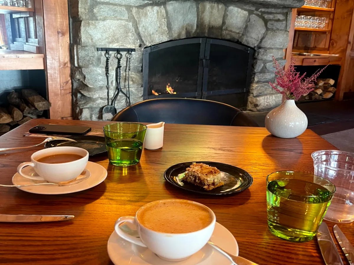 The image captures a welcoming dining space with a stone fireplace and a table set for a cozy gathering.