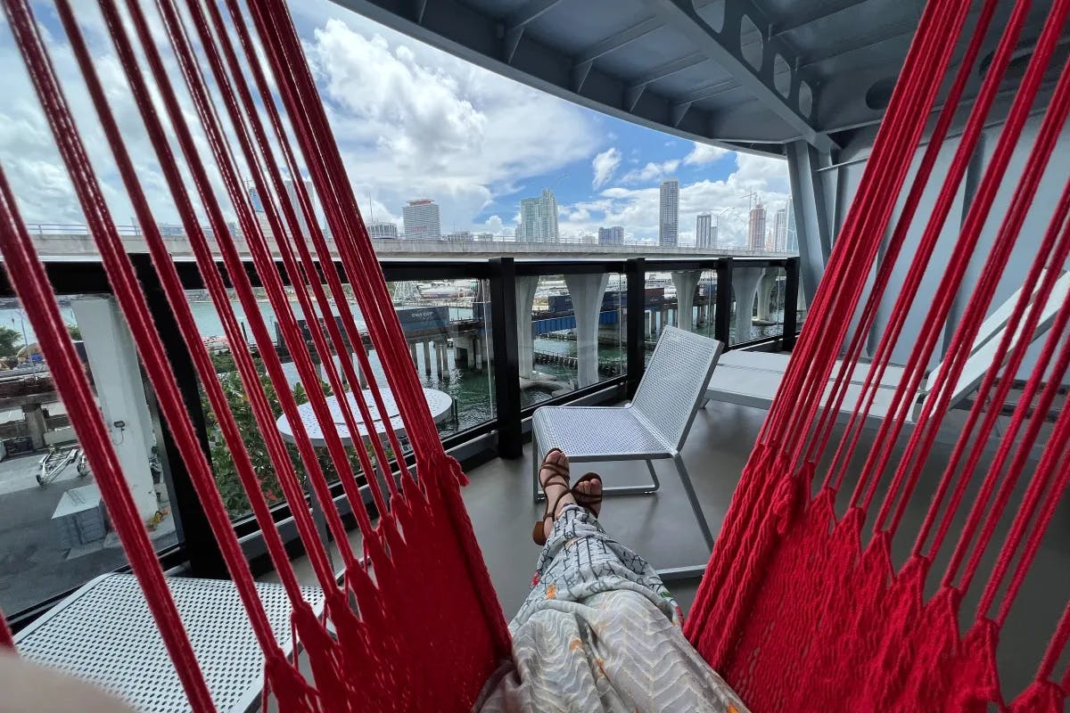 A picture of a lady lying on a red hammock on the cruise ship with her legs crossed.