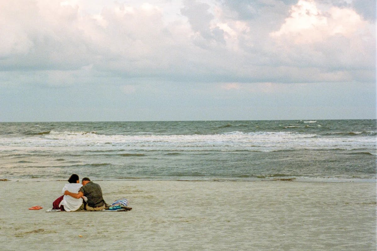 A couple sitting near the beach during daytime.