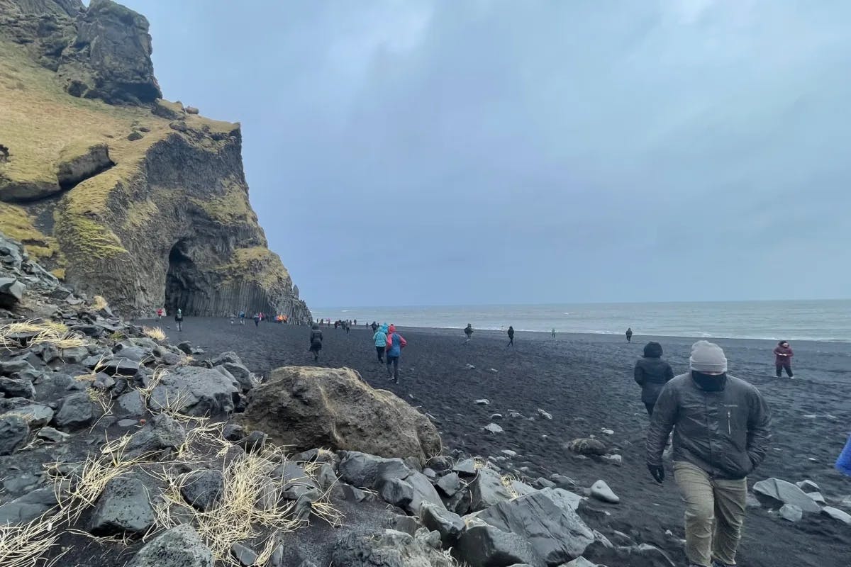 A picture of people walking near the shore in daytime.