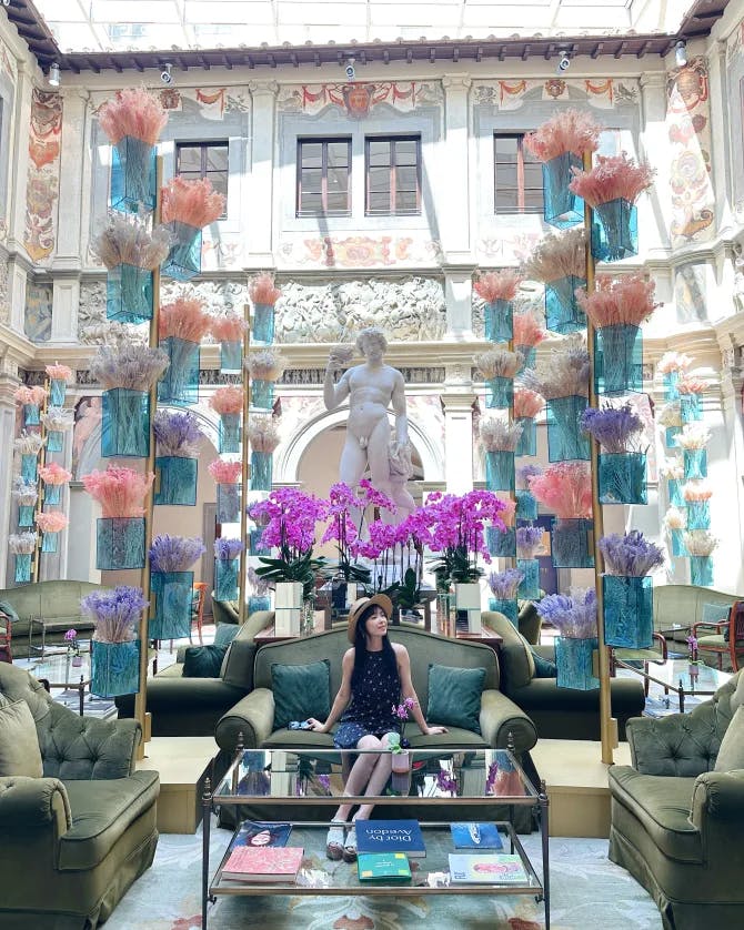 Advisor sitting on an upholstered couch in a hotel lobby with glass walls and a white statue of a man behind her