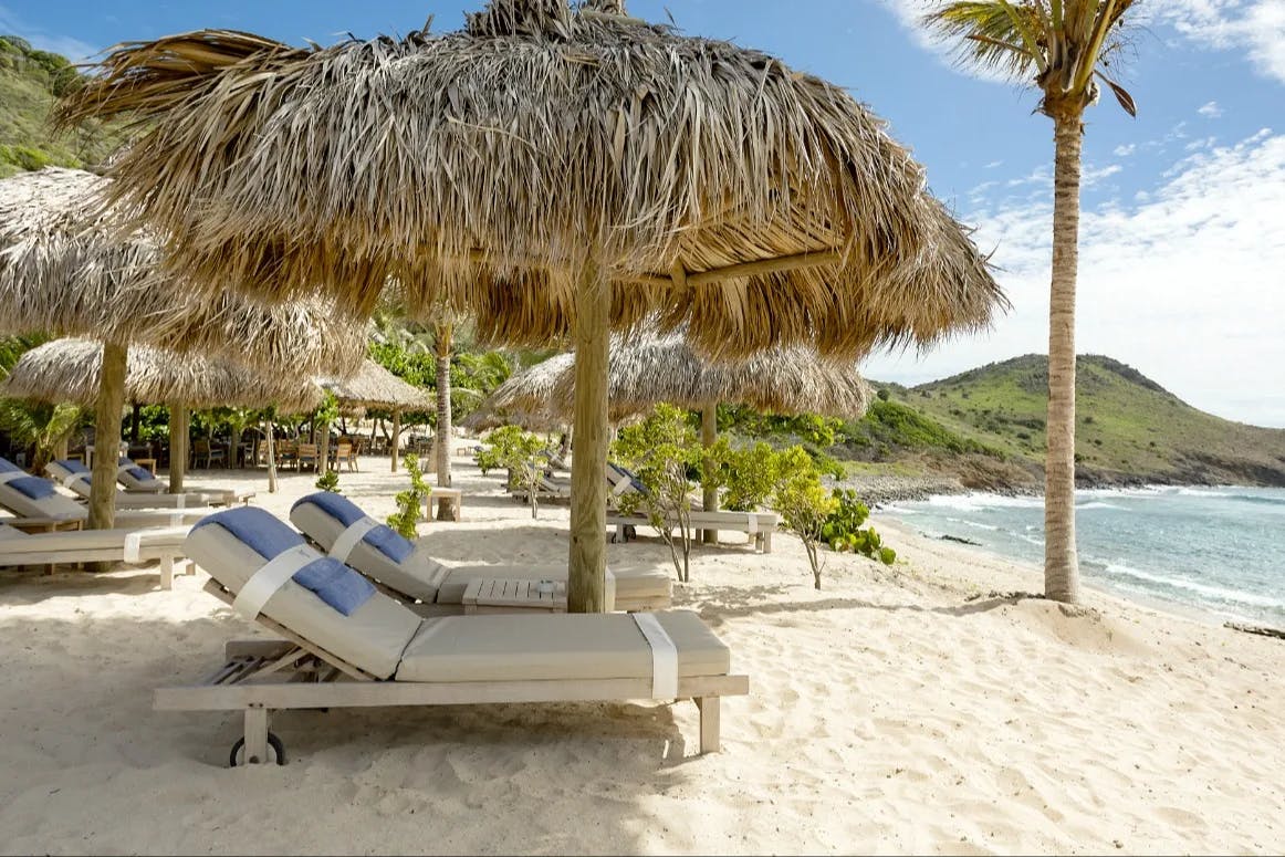 cushioned loungers and towels on a white beach with turquoise sea