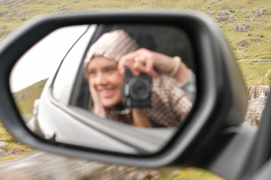 Advisor takes a selfie in the rearview mirror of a car.