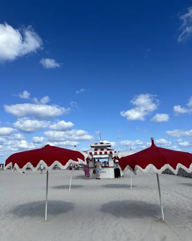 Two red and white umbrellas in the sand on a clean white sand beach under sunny skies