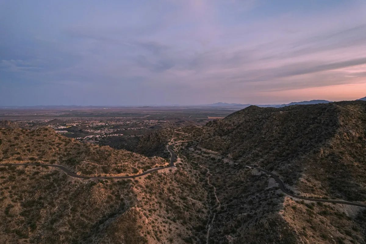 Aerial view of rolling hills under a pink and purple sky at dusk. 