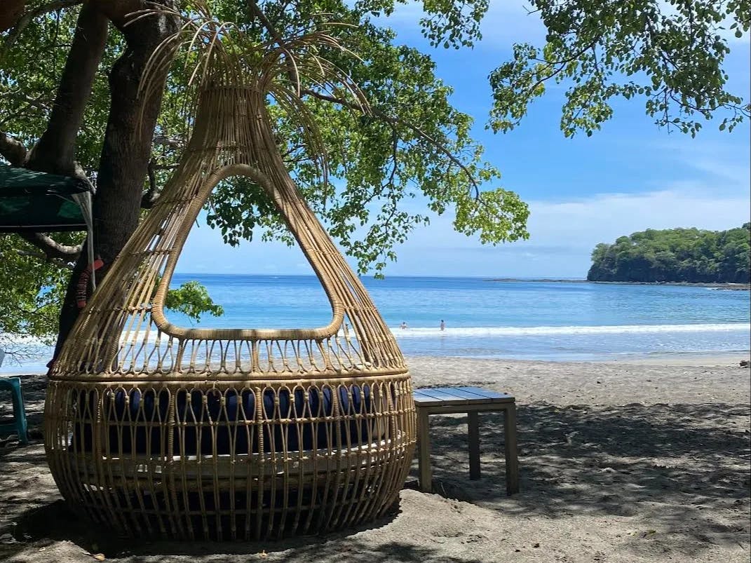 A large round wicker couch on the beach