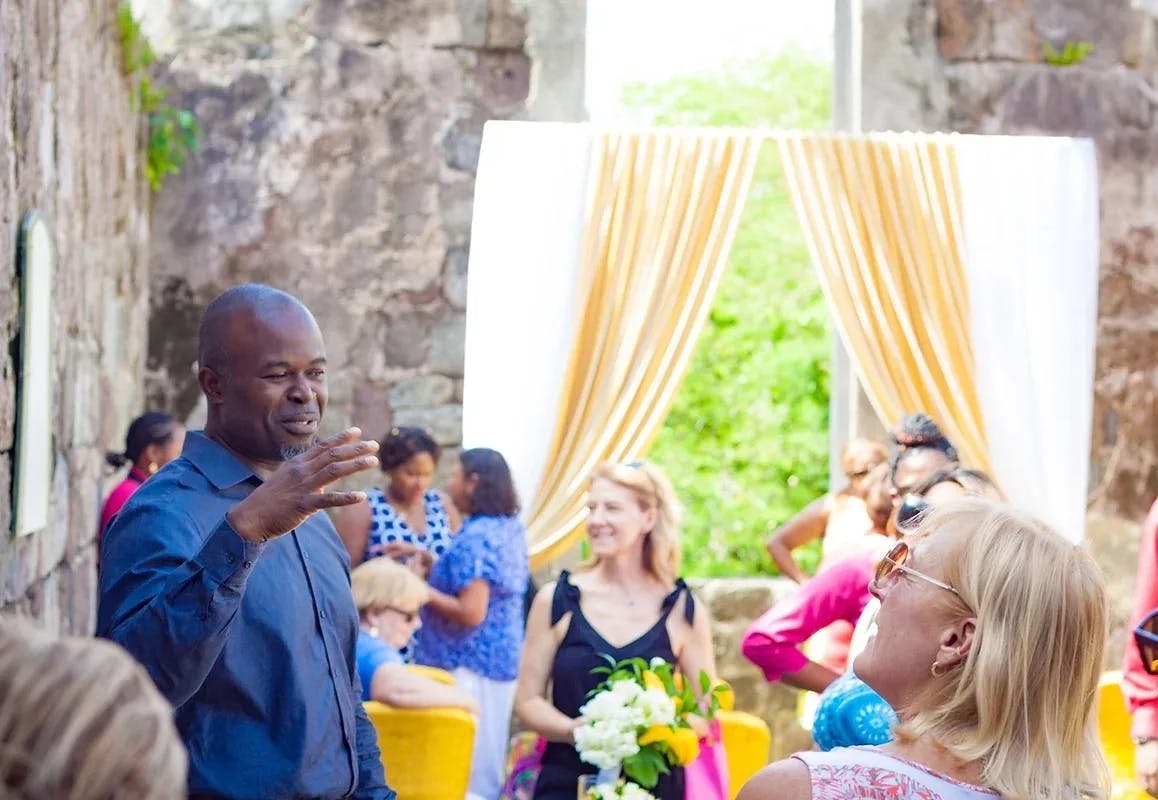 a man in a blue shirt addresses a group of people in an outdoor courtyard