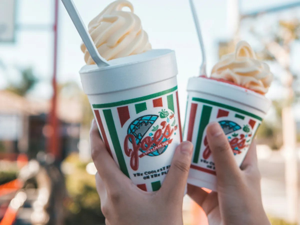 The image portrays two hands offering soft-serve ice cream, with a sign in the background hinting at the purchase location.