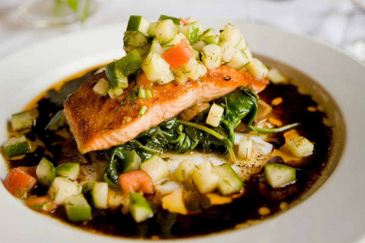 Meal on a white plate with salmon and zucchini.