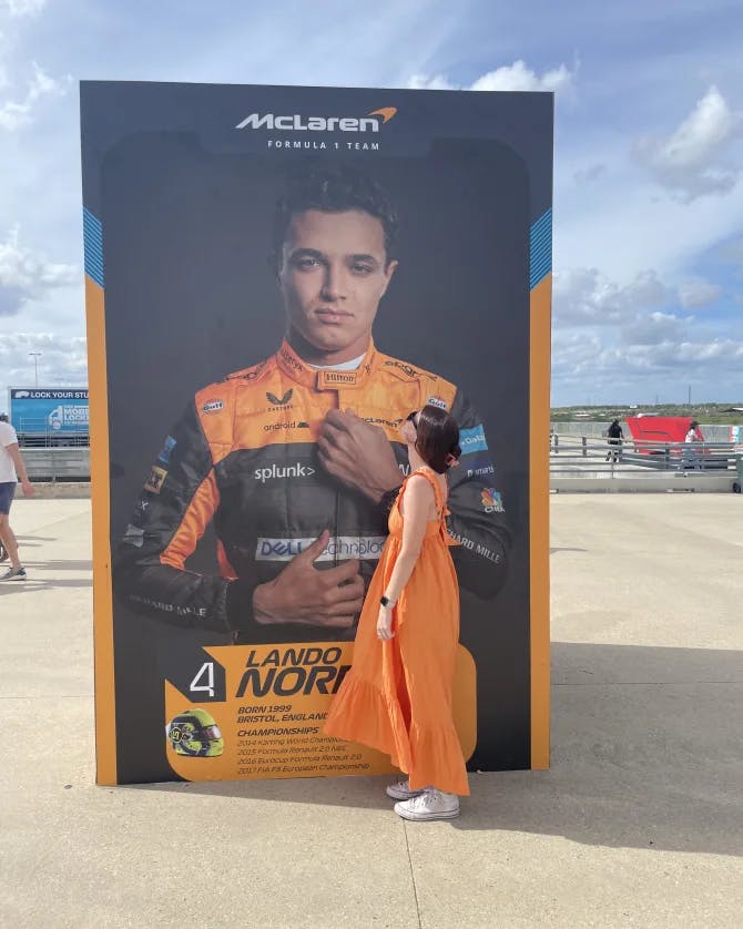 Picture of Bridget wearing an orange dress with an advertisement of an athlete placed outside