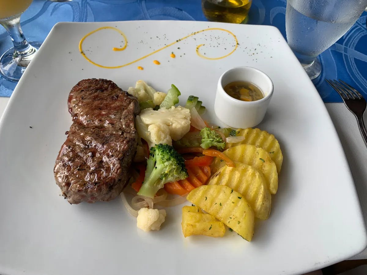 A picture of a meat steak with veggies served on a plate.