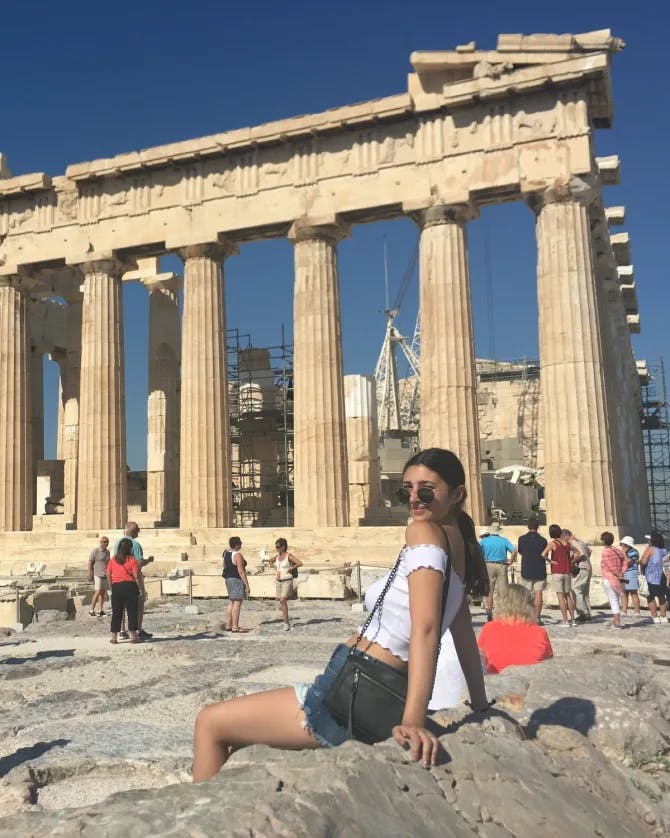 Travel advisor in front of a building ruin with pillars.