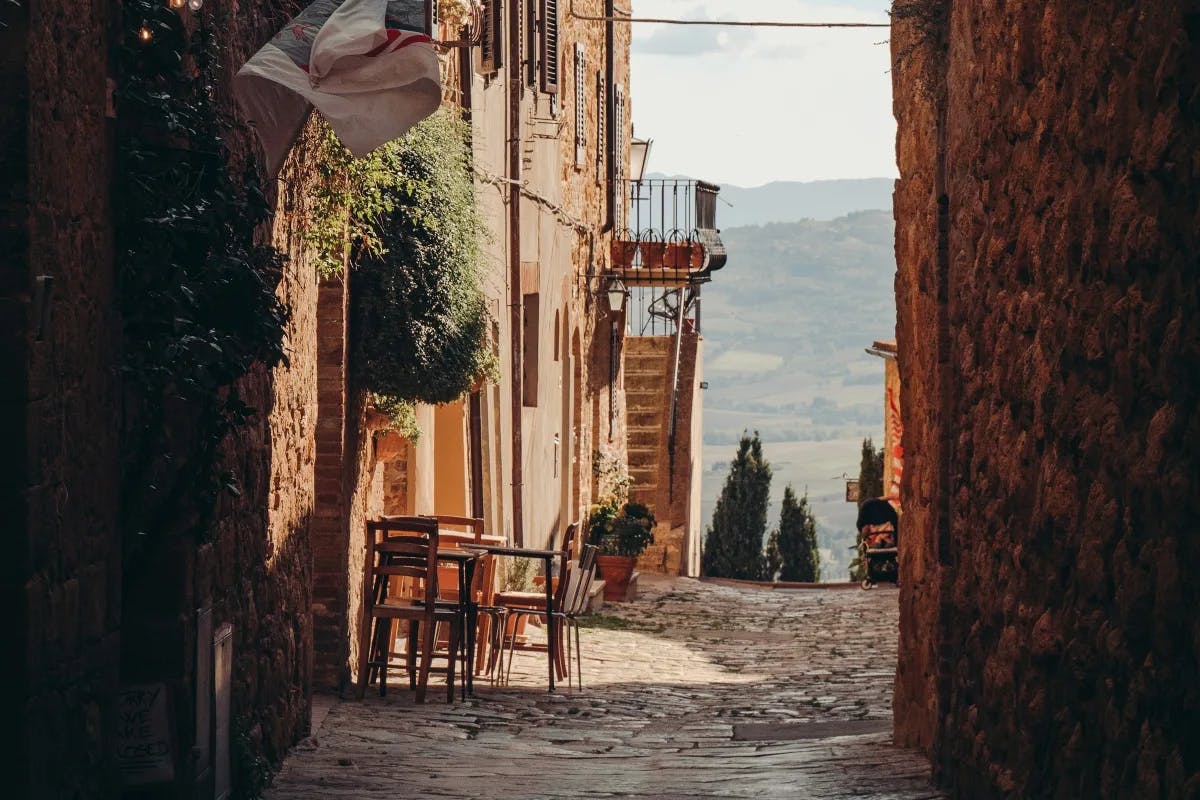 A narrow street with stone buildings on both sides and a stone road in Pienza, Italy.