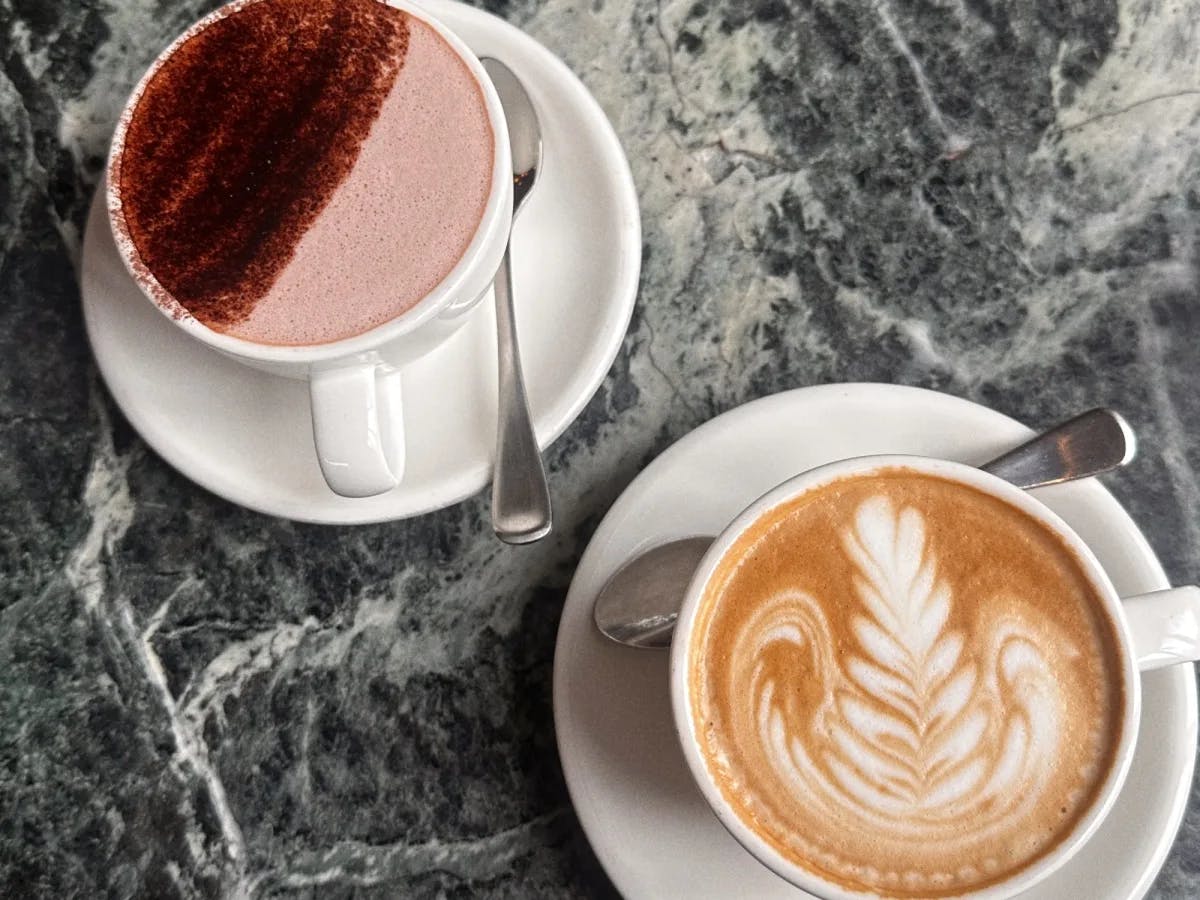 A flat lay of two coffee drinks on a granite countertop.